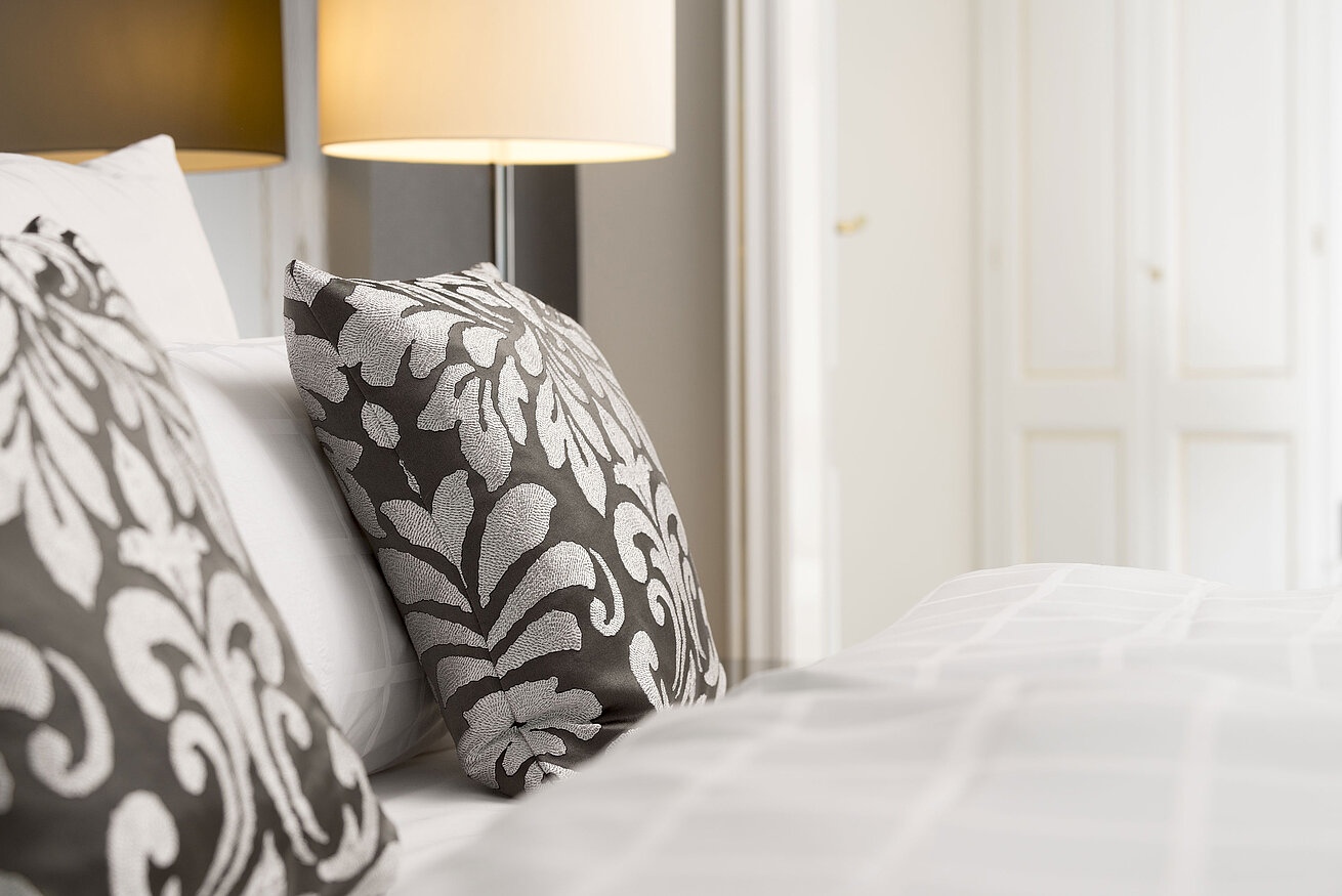 Elegante dekorative Kissen mit floralem Muster auf dem Bett in der Luxus-Suite im Maritim Hotel Bonn.