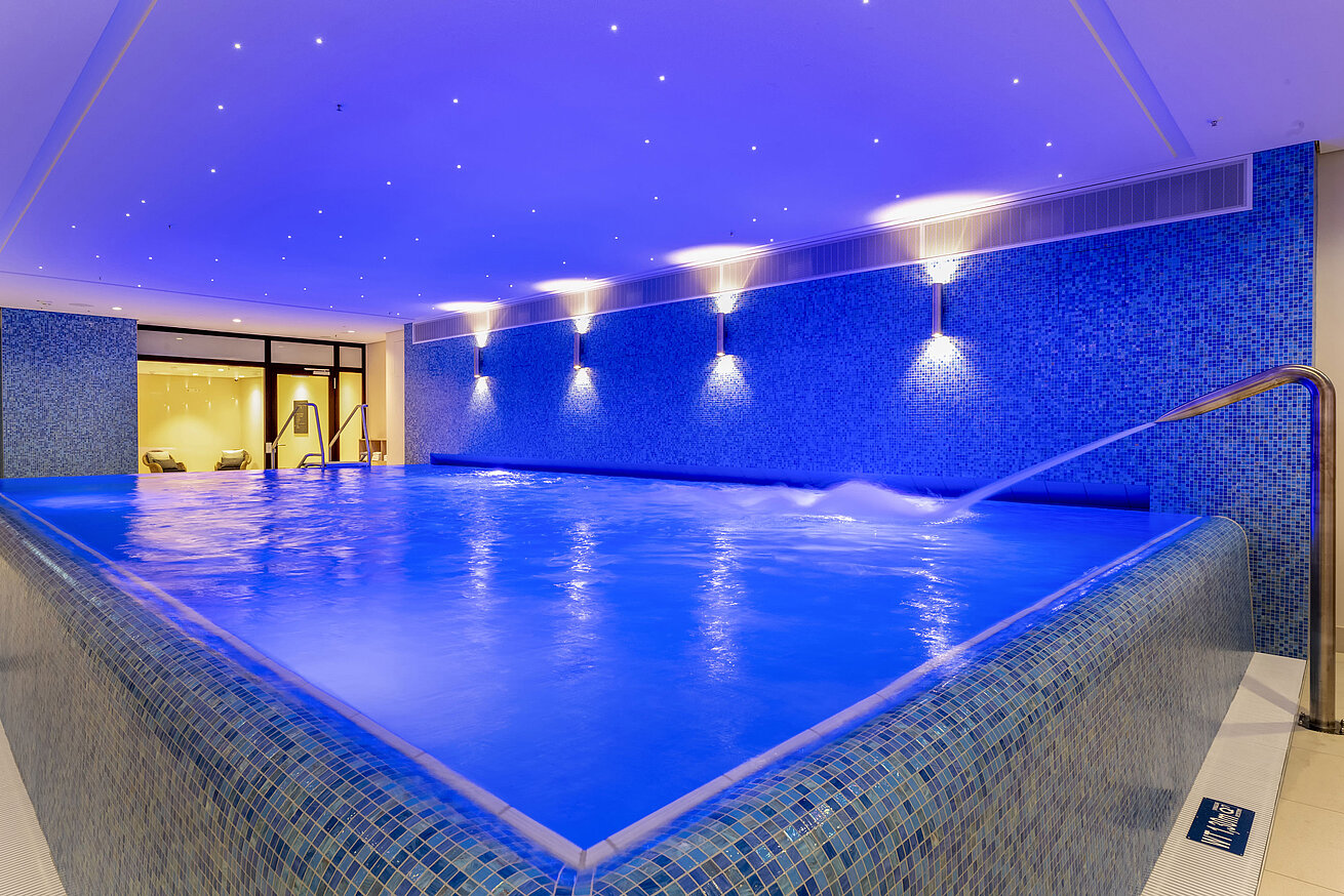 Beleuchteter Infinity-Pool im Maritim Hotel Ingolstadt mit entspannendem Wasserstrahl.